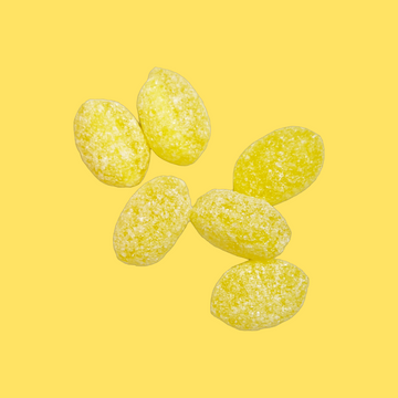 Five yellow sugar-coated candy pieces arranged on a solid yellow background.