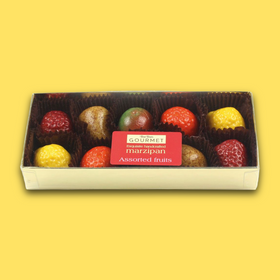 Box of gourmet marzipan assorted fruits on a yellow background