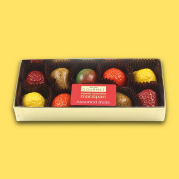 Box of gourmet marzipan assorted fruits on a yellow background