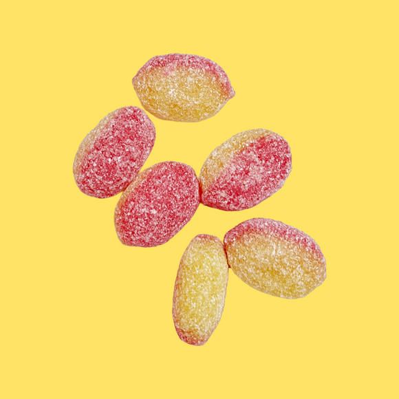 Five sugar-coated candy pieces in red and yellow-orange colors, arranged on a solid yellow background.