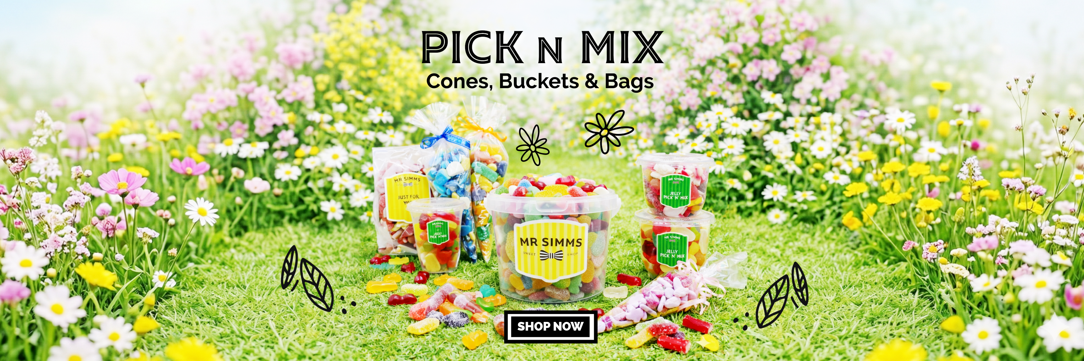 Packaging of 'Pick n Mix' cones, buckets, and bags on a grassy field with flowers.